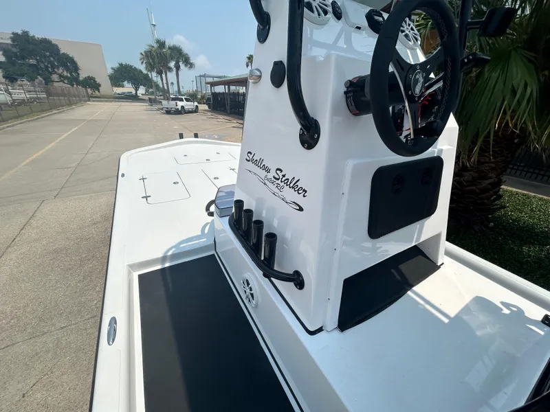 Slide: The Image of 2025 Shallow Stalker 240 RC Elite boat, white console, docked on a sunny day. - 10