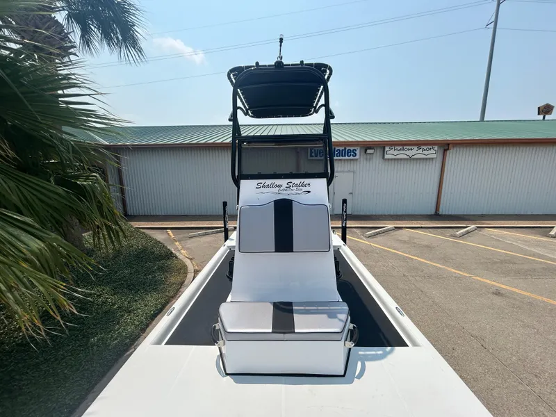 Slide: The Image of Shallow Stalker 240 RC Elite 2025 boat with seating and T-top in parking lot. - 13
