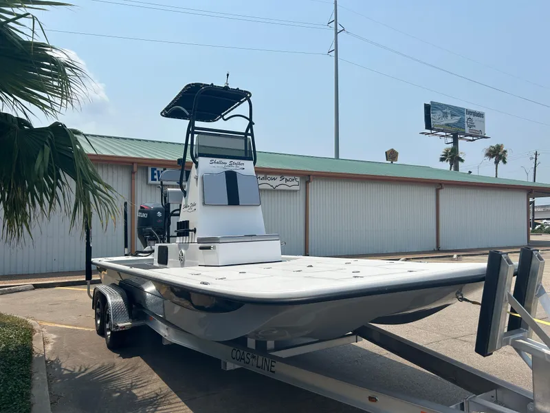 Slide: The Image of 2025 Shallow Stalker 240 RC Elite boat on a trailer in a parking lot. - 2