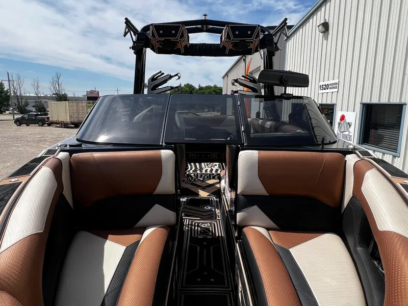 Slide: The Image of 2021 Centurion Ri245 boat interior with brown and white seating, docked outdoors. - 11
