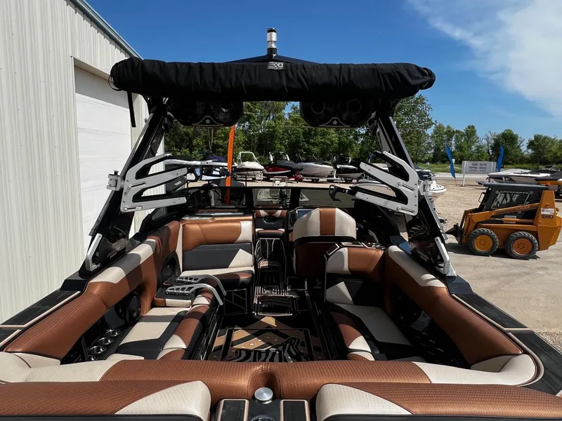 Slide: The Image of 2021 Centurion Ri245 boat interior with brown and white seating, docked outdoors. - 12
