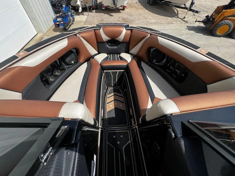 Slide: The Image of 2021 Centurion Ri245 boat interior with brown and beige seating, cup holders, and stylish flooring. - 13