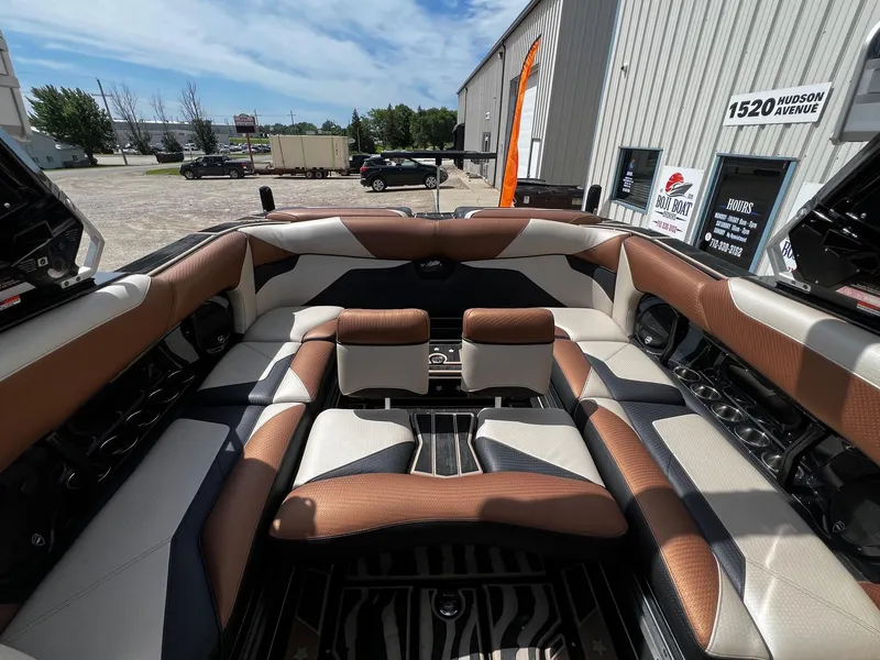 Slide: The Image of 2021 Centurion Ri245 boat interior with brown and white seating, docked outside dealership. - 30