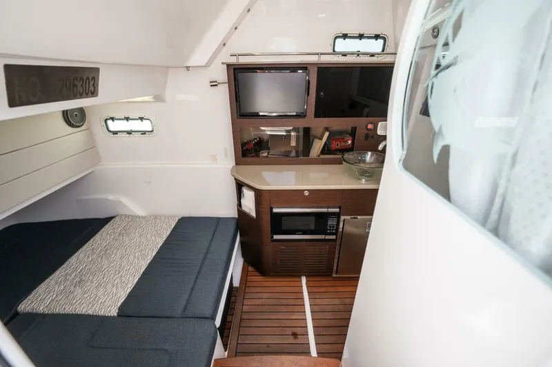Slide: The Image of 2019 Everglades 435 Center Console cabin with bed, kitchenette, and TV. - 16