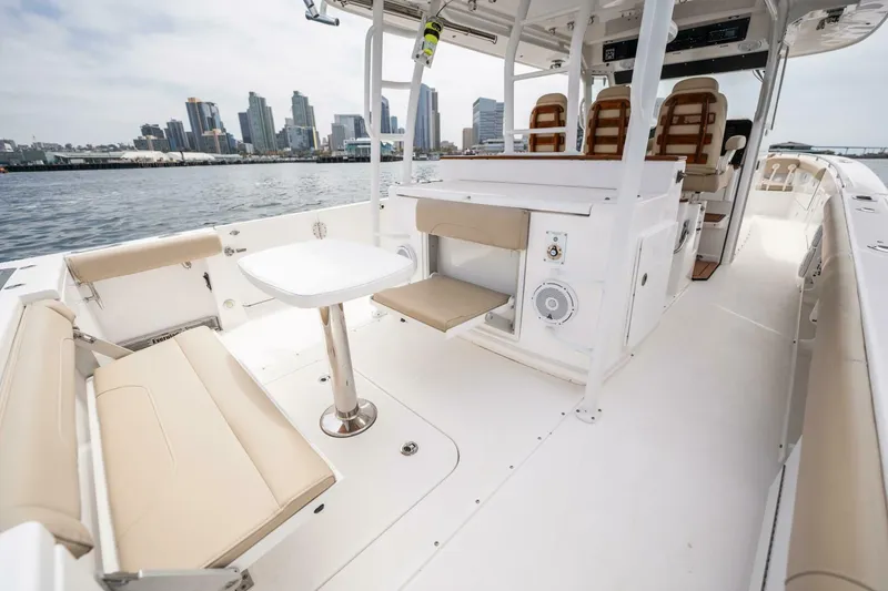 Slide: The Image of 2019 Everglades 435 Center Console boat interior with seating and table, docked near city skyline. - 25