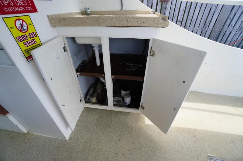Slide: The Image of Open cabinet with sink on 1989 Markley 35 Ft. Deadrise boat, featuring storage space. - 30