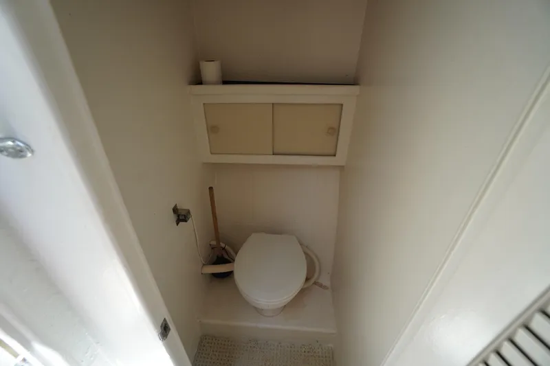 Slide: The Image of Compact bathroom on a 1989 Markley 35 Ft. Deadrise boat, featuring a toilet and storage cabinet. - 36