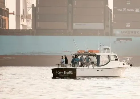 Slide: The Image of 1998 Markley 35 Ft. Deadrise boat named Corn Bread with people fishing, cargo ship in background. - 4