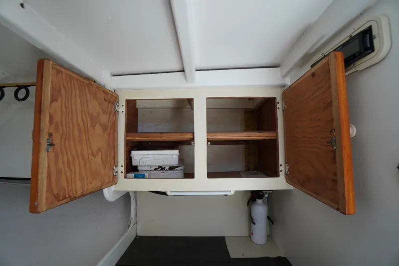 Slide: The Image of Open wooden cabinet inside a 1989 Markley 35 Ft. Deadrise boat, with storage items. - 41