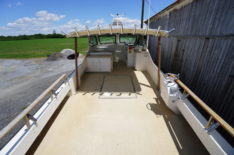 Slide: The Image of 1989 Markley 35 Ft. Deadrise boat with spacious deck, docked beside a wooden structure. - 56