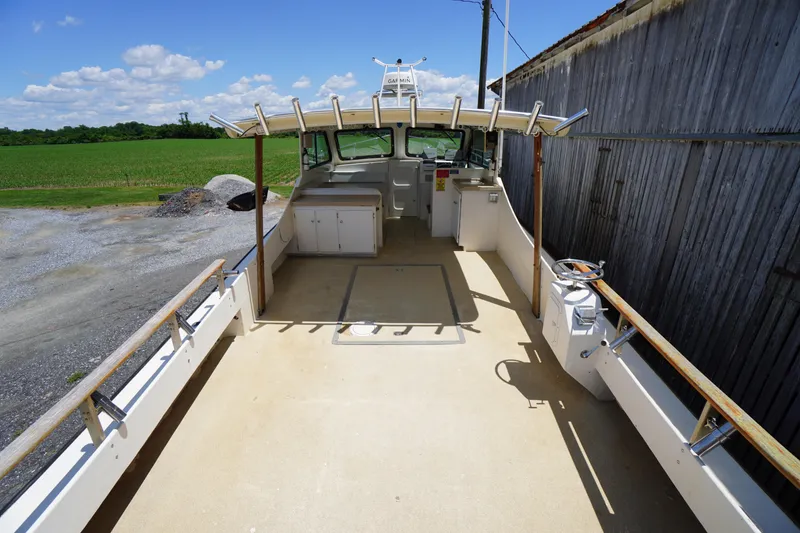 Slide: The Image of 1989 Markley 35 Ft. Deadrise boat with spacious deck and cabin, docked outdoors. - 57