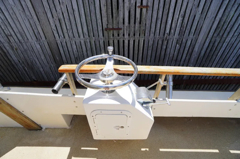 Slide: The Image of 1989 Markley 35 Ft. Deadrise boat helm with wooden rail and metal steering wheel. - 58