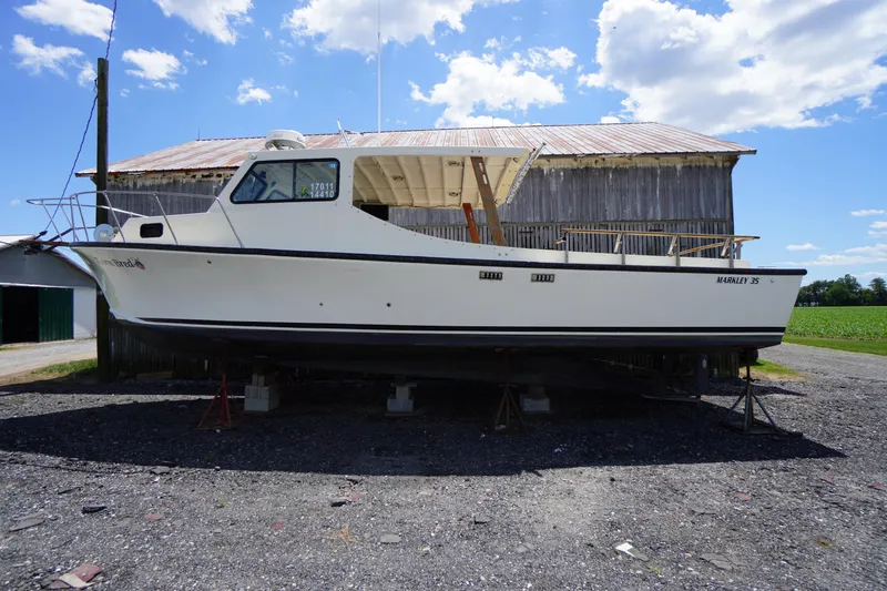 Slide: The Image of 1989 Markley 35 Ft. Deadrise boat on stands, rustic barn backdrop, sunny day. - 71
