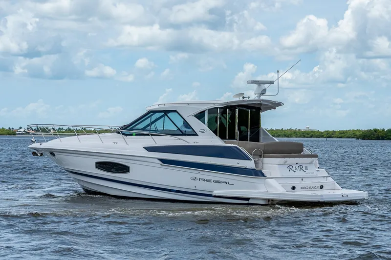 Slide: The Image of 2015 Regal 46 Sport Coupe yacht cruising on a calm sea under a partly cloudy sky. - 12