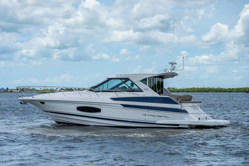 Slide: The Image of 2015 Regal 46 Sport Coupe yacht cruising on a calm sea under a partly cloudy sky. - 13
