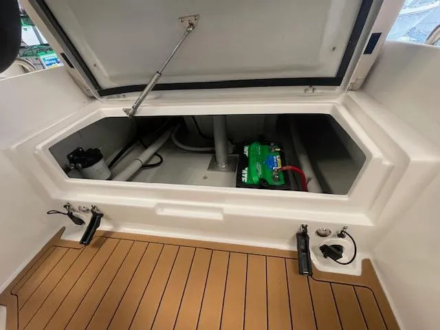 Slide: The Image of 2024 Northstar Axis 4.2 boat storage compartment with battery and wooden flooring. - 9
