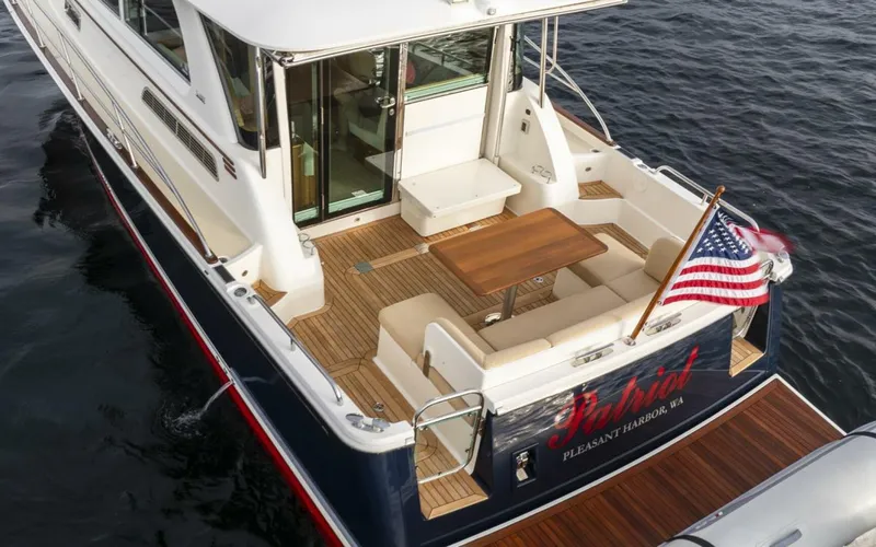 Slide: The Image of 2018 Sabre 45 Salon Express yacht with American flag, elegant deck seating, and wooden table. - 9
