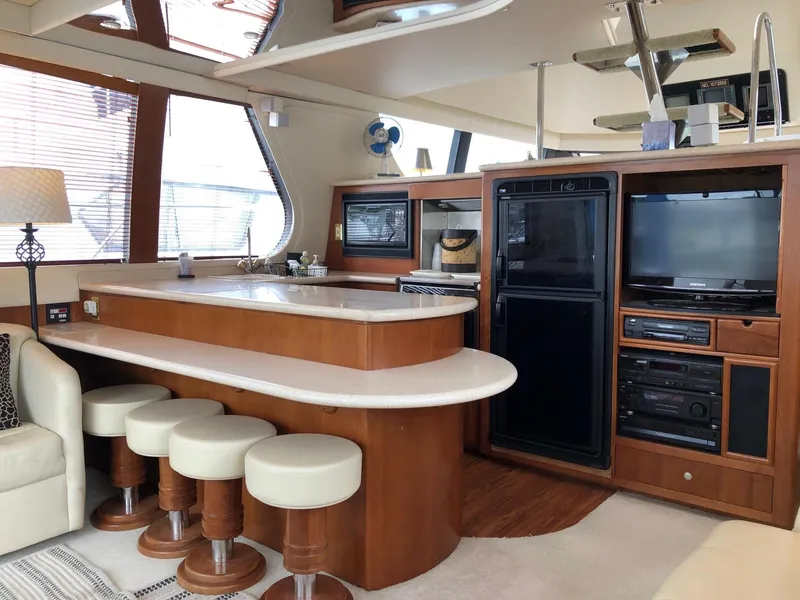 Slide: The Image of Interior of 1998 Carver 530 Voyager Pilothouse with bar stools, kitchen, and entertainment center. - 10