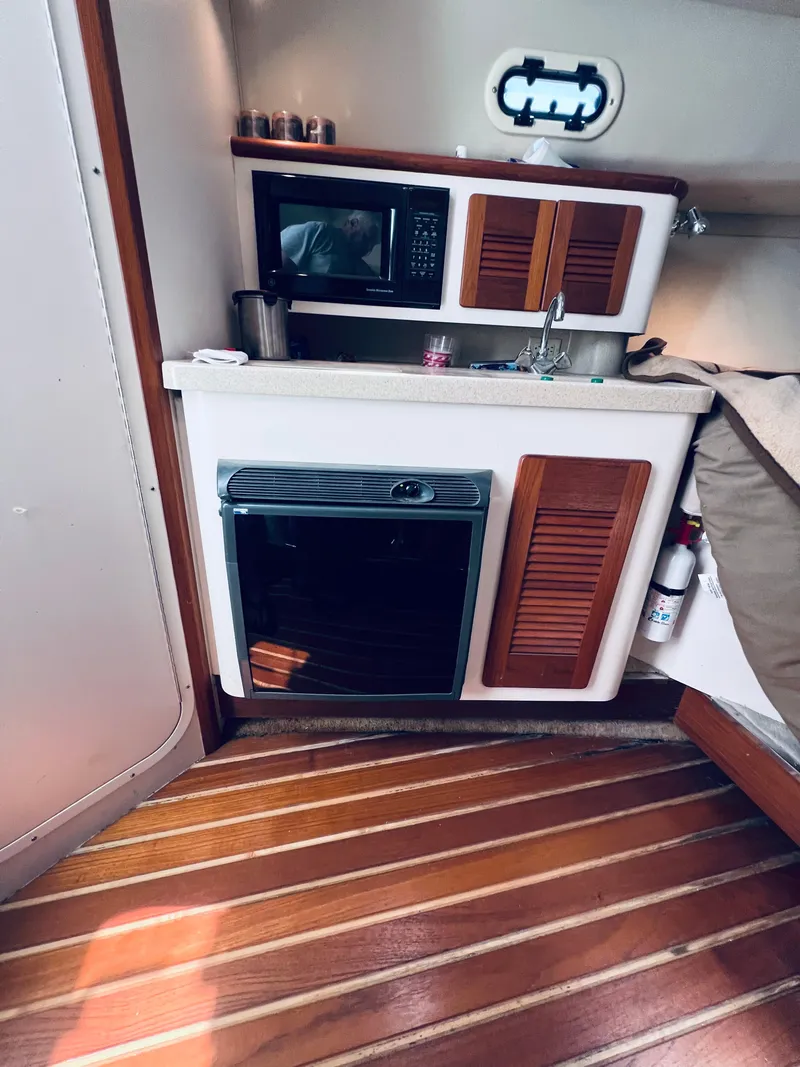 Slide: The Image of Compact kitchen area in a 2002 Pursuit 3000 Express boat with microwave and oven. - 15
