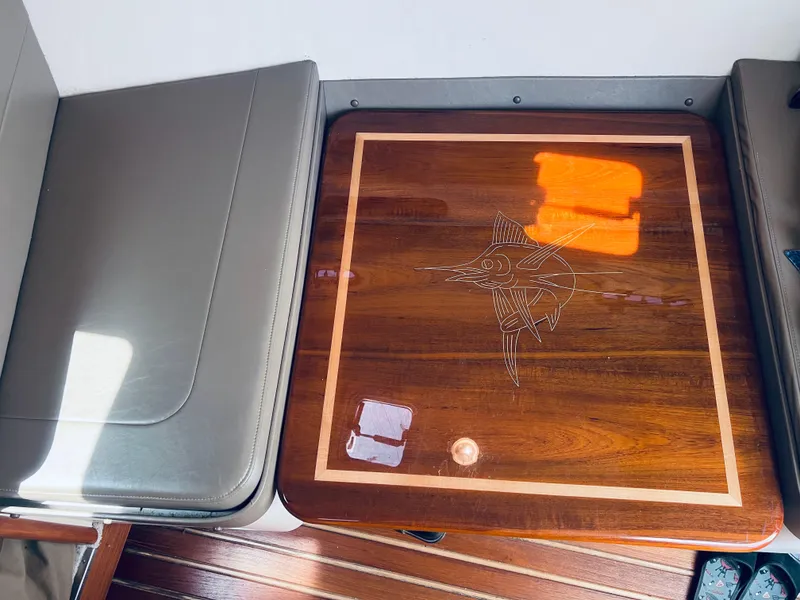 Slide: The Image of Wooden table with marlin design on a 2002 Pursuit 3000 Express boat interior. - 16