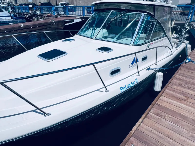 Slide: The Image of 2002 Pursuit 3000 Express boat docked, white exterior, named "FinLander II". - 3