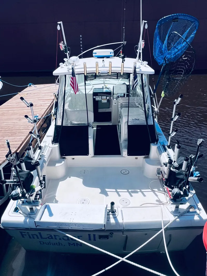 Slide: The Image of 2002 Pursuit 3000 Express boat docked, equipped with fishing gear and American flags. - 7