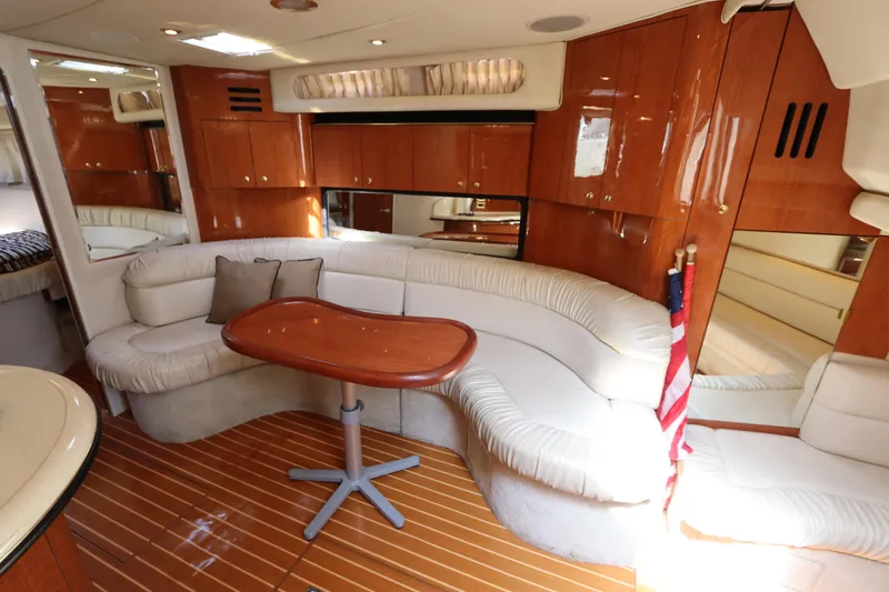 Slide: The Image of 1999 Sea Ray 380 Sundancer interior with curved seating, wooden table, and polished cabinetry. - 30