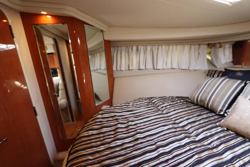 Slide: The Image of 1999 Sea Ray 380 Sundancer cabin with striped bedding and mirrored closet. - 33