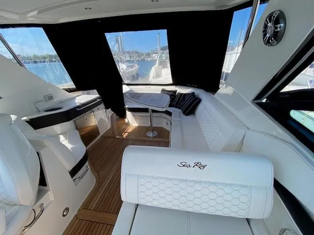 Slide: The Image of Interior of 2022 Sea Ray 320 Sundancer Outboard with white seating and wood flooring. - 10