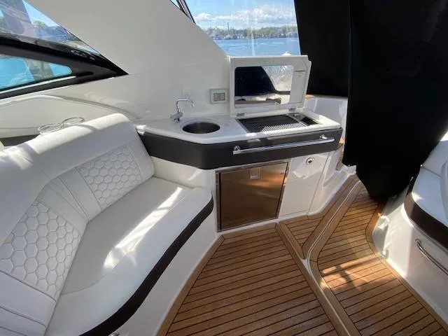 Slide: The Image of 2022 Sea Ray 320 Sundancer Outboard interior with seating, kitchenette, and wooden flooring. - 12