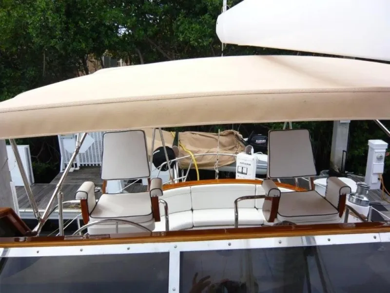 Slide: The Image of 1990 Cheoy Lee Sloop with cushioned seating and canopy, docked in a marina. - 19