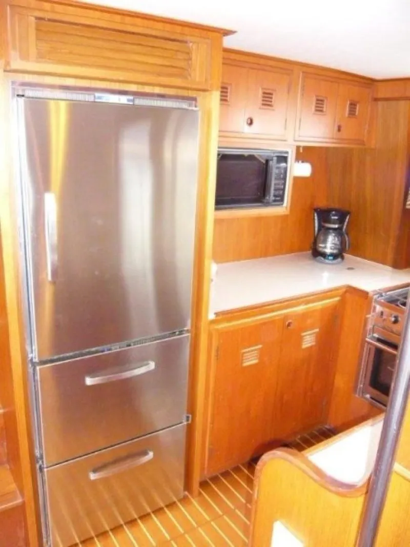 Slide: The Image of 1990 Cheoy Lee Sloop kitchen with stainless steel fridge and wooden cabinetry. - 40