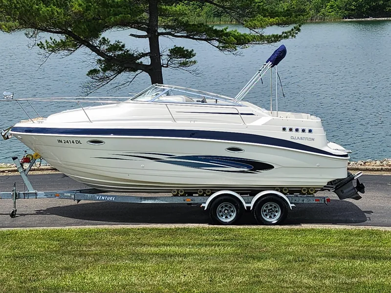 Slide: The Image of 2008 Glastron GT 249 boat on trailer by a lake. - 0