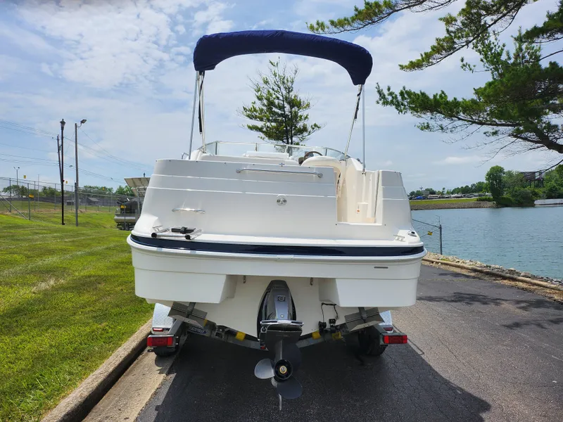 Slide: The Image of 2008 Glastron GT 249 boat with blue canopy on trailer by lakeside. - 2