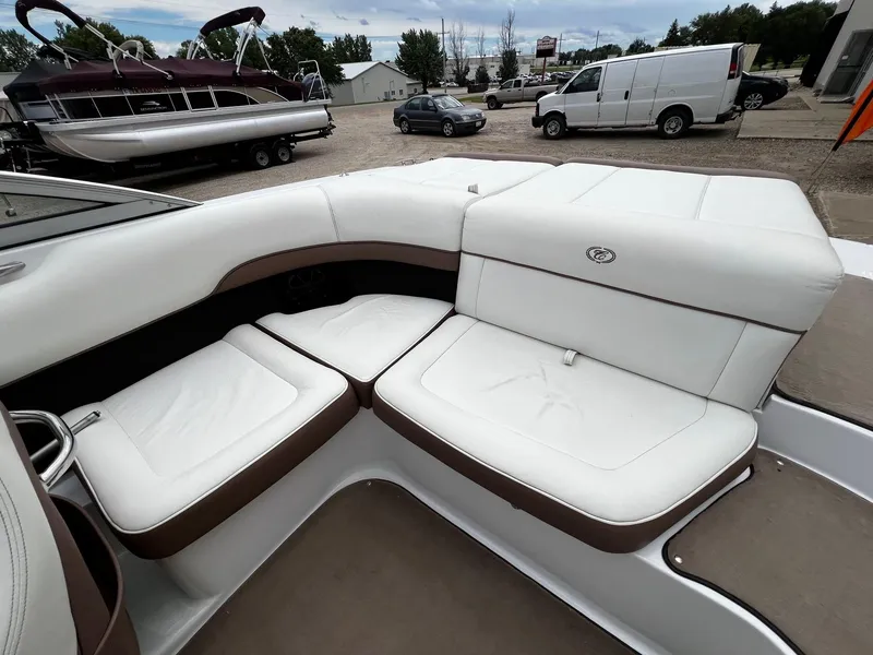 Slide: The Image of 2011 Cobalt 200 boat with white and brown cushioned seating, parked near other boats and vehicles. - 19