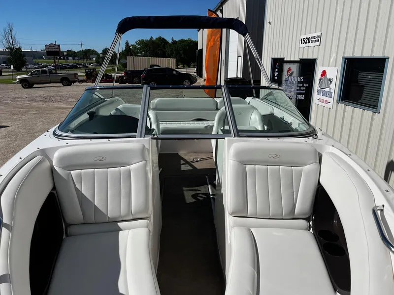 Slide: The Image of 2004 Regal 2200 Bowrider boat with white leather seats, parked outside a building. - 3