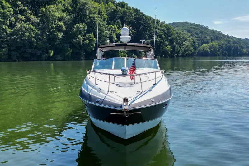 Slide: The Image of 2008 Cruisers Yachts 330 Express on a serene lake with lush green surroundings. - 9