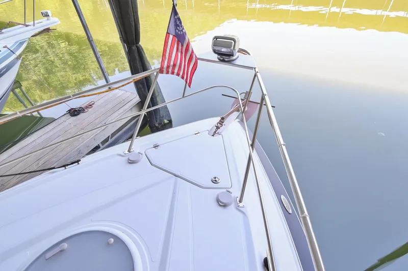 Slide: The Image of 2008 Cruisers Yachts 330 Express bow with American flag docked by calm water. - 37