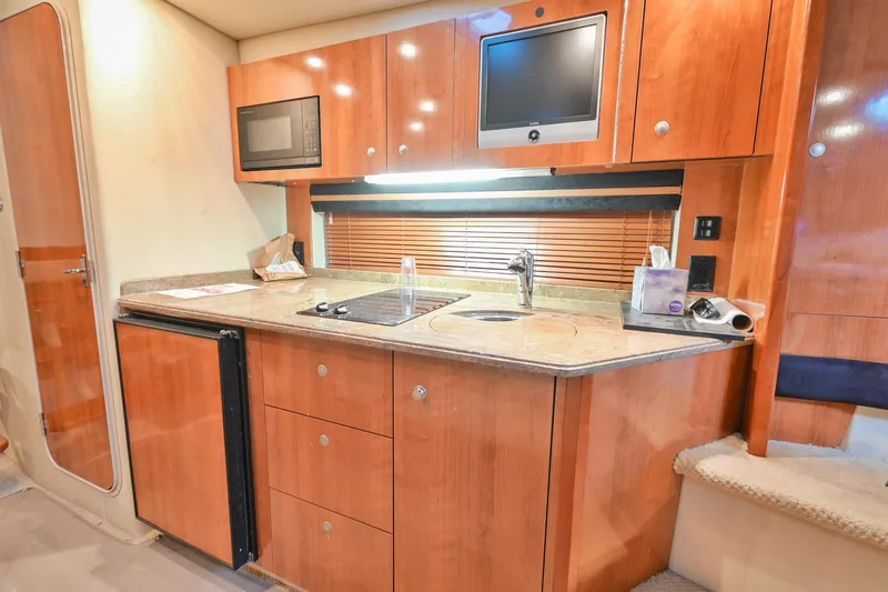 Slide: The Image of 2008 Cruisers Yachts 330 Express kitchen with microwave, TV, sink, and wooden cabinetry. - 45
