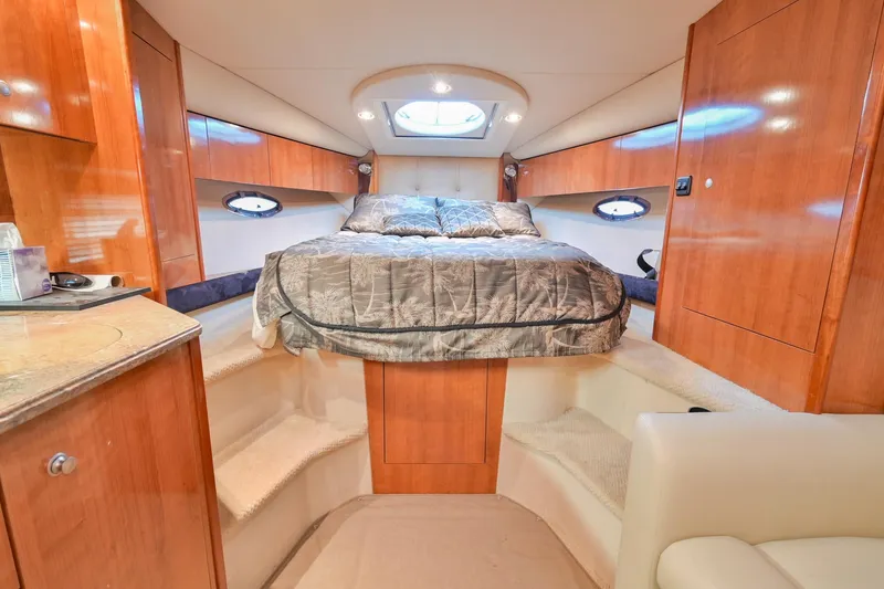 Slide: The Image of 2008 Cruisers Yachts 330 Express cabin with bed, wooden cabinetry, and porthole windows. - 47
