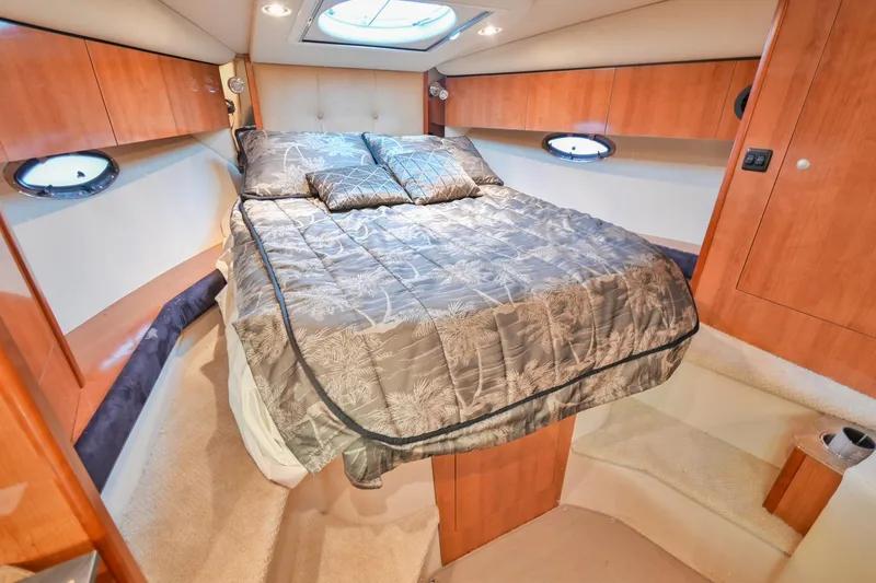 Slide: The Image of 2008 Cruisers Yachts 330 Express cabin with a cozy bed and wooden cabinetry. - 48