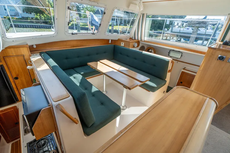 Slide: The Image of Interior of 2002 PDQ Power Catamaran MV/34 Passagemaker with green cushioned seating and wooden table. - 22