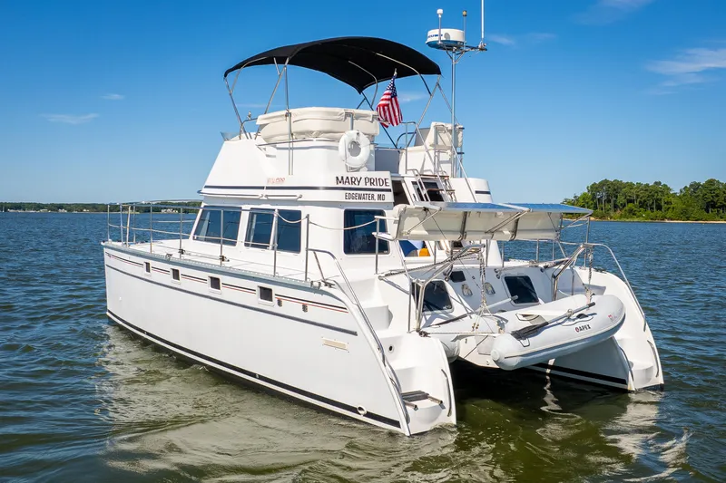 Slide: The Image of 2002 PDQ Power Catamaran MV/34 Passagemaker on water, rear view with dinghy. - 8