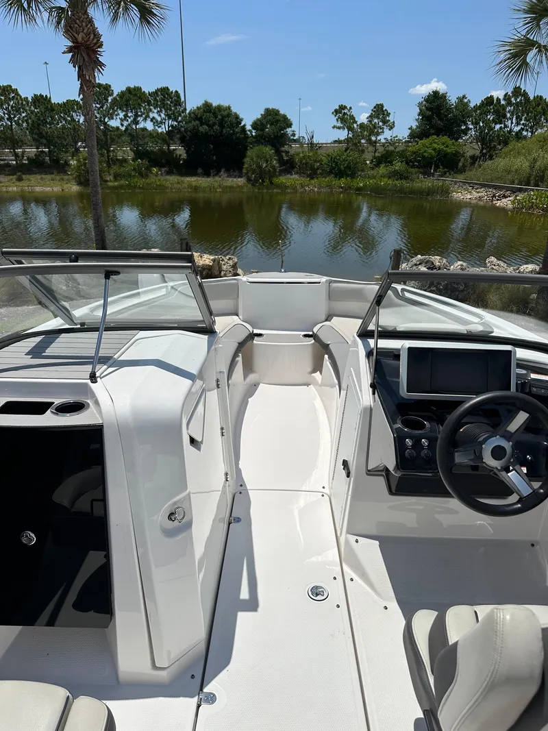 Slide: The Image of 2022 Yamaha Boats SX250 interior with steering console, white seating, and lake view. - 24