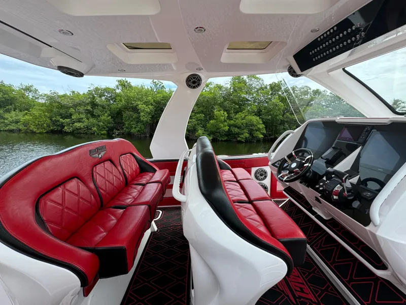 Slide: The Image of Luxurious 2022 Deep Impact 399 boat interior with red and black seating, modern dashboard. - 16