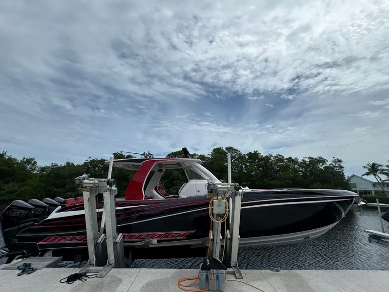 Slide: The Image of 2022 Deep Impact 399 boat on lift, under cloudy sky. - 2