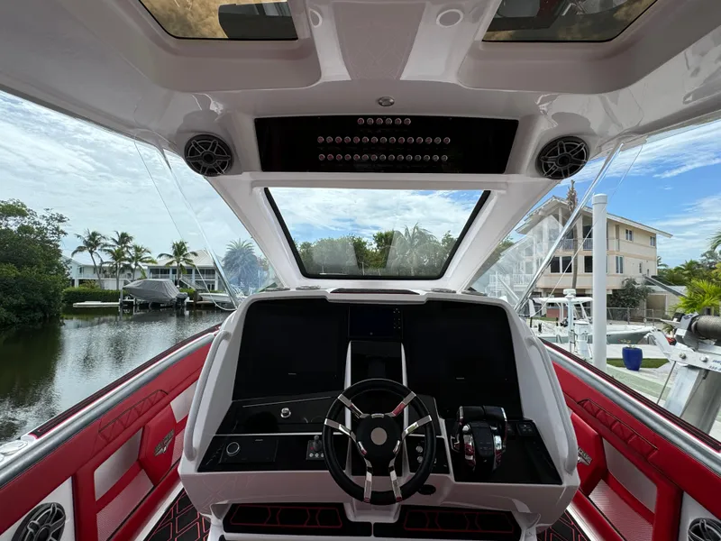 Slide: The Image of Interior view of 2022 Deep Impact 399 boat cockpit with red seating and modern controls. - 24