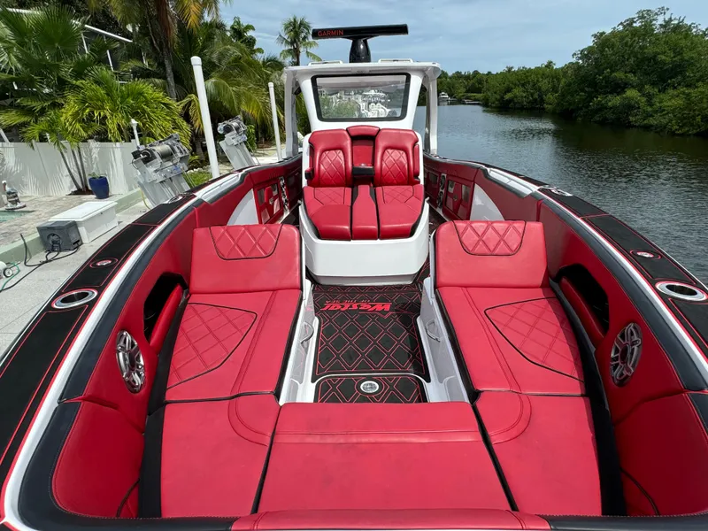 Slide: The Image of Luxurious 2022 Deep Impact 399 boat with red seating, docked by a scenic waterway. - 30