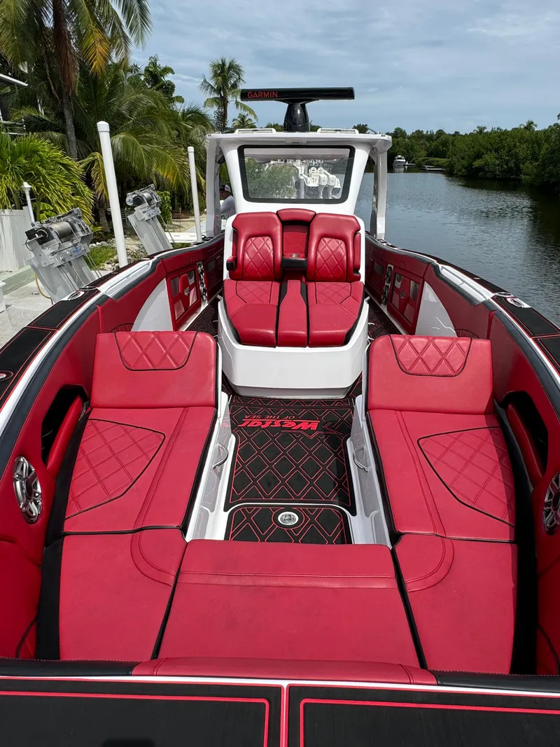 Slide: The Image of Luxurious 2022 Deep Impact 399 boat with red seating, docked by a scenic waterway. - 31