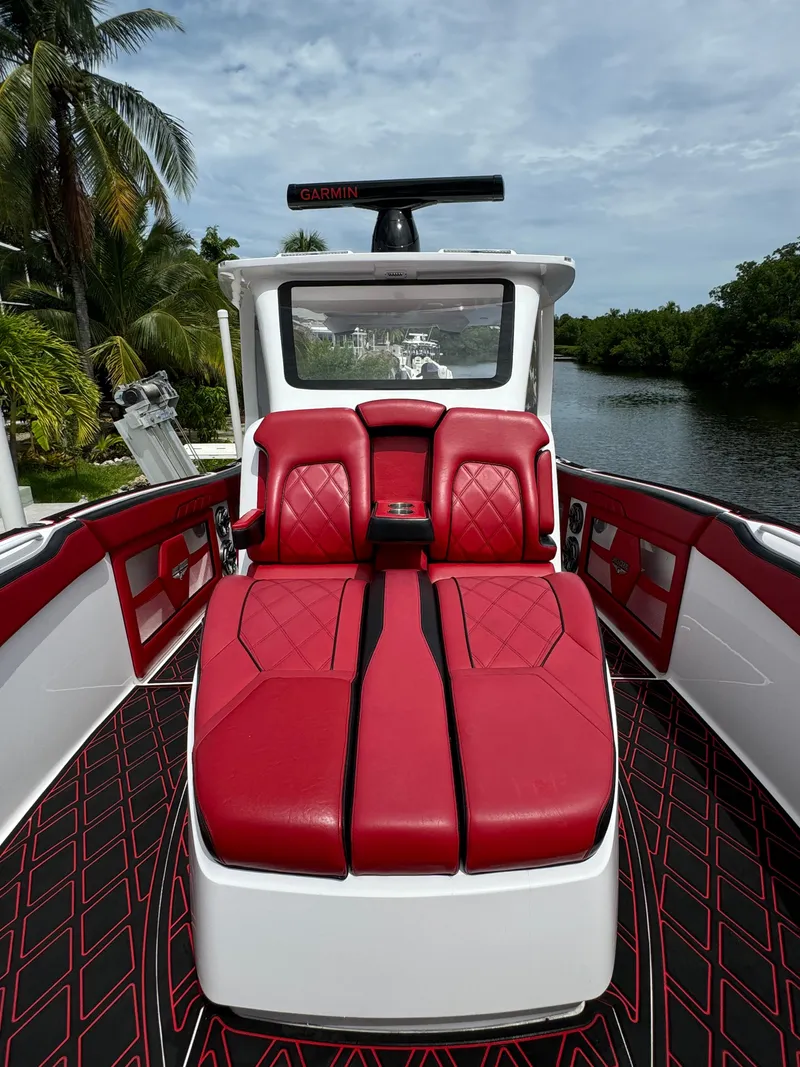 Slide: The Image of Luxurious 2022 Deep Impact 399 boat with red seating, docked by a scenic waterway. - 32